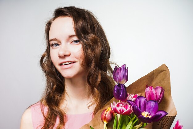 Glimlachende gelukkige mooie vrouw met een groot boeket bloemen, ter ere van Wereldvrouwendag