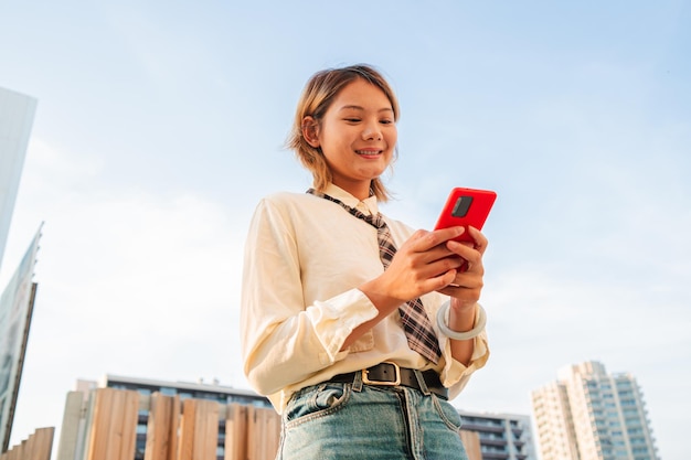 Glimlachende gelukkige tienerchines die haar smartphone gebruikt en online chatteert of op het internet surft