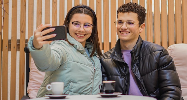 Glimlachende gelukkige vrienden die selfie nemen Jongeren die koffie in staaf drinken