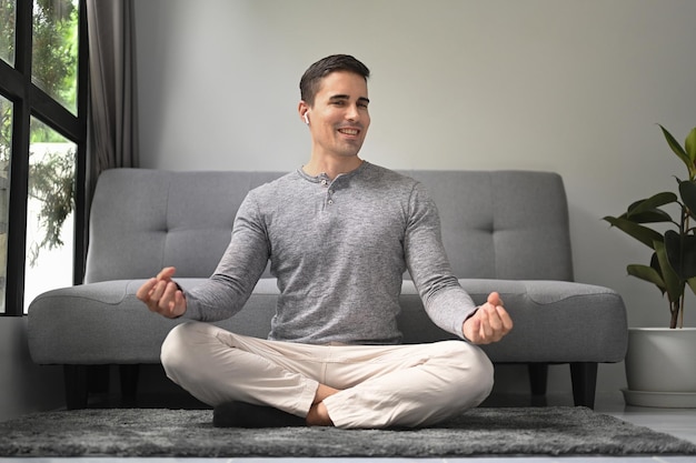 Glimlachende gezonde man die thuis yoga beoefent Meditatie en gezond levensstijlconcept