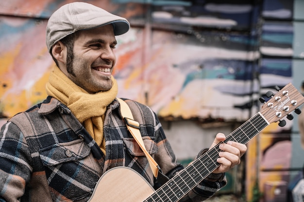 Glimlachende gitaristmens die op de straat spelen