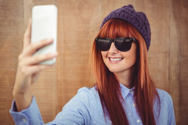 Glimlachende hipster vrouw die selfie neemt