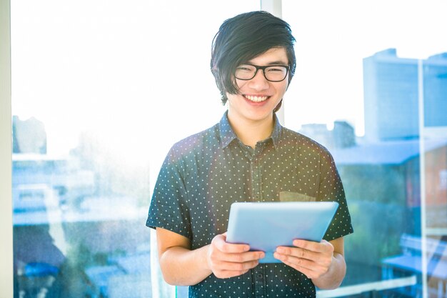 Glimlachende hipster zakenman die tablet in bureau gebruiken