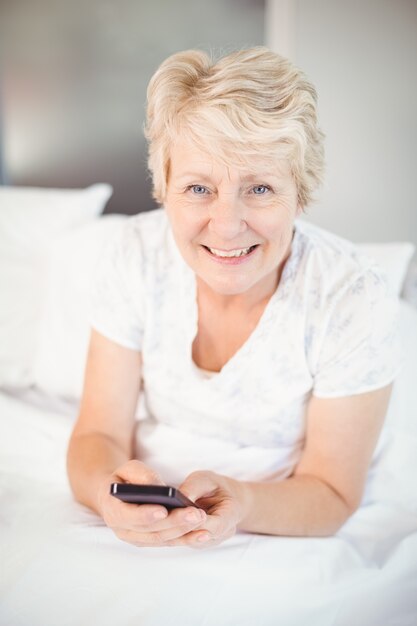 Glimlachende hogere vrouw die telefoon met behulp van