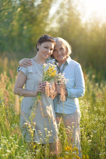 Glimlachende hogere vrouw met volwassen dochter met bloemen in park