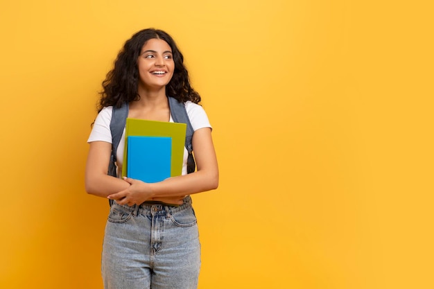 Glimlachende Indiase studente met notitieboekjes die naar kopieerruimte kijken