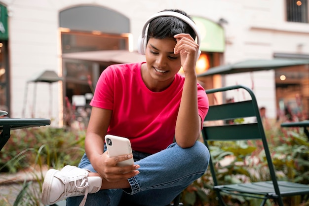 Glimlachende Indiase vrouw die mobiele telefoon gebruikt, sms leest, online communiceert op straat