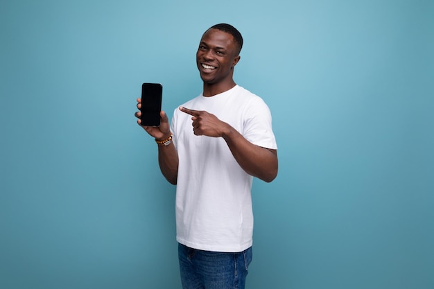 Glimlachende jaar oude Amerikaanse mannelijke volwassen manager in wit t-shirt met smartphone scherm