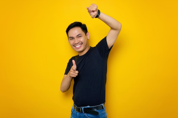 Glimlachende jonge Aziatische man in casual tshirt wijzende vinger naar camera geïsoleerd op gele achtergrond Mensen lifestyle concept