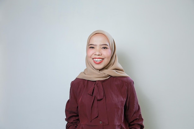 Glimlachende jonge Aziatische moslimvrouw voelt zich zelfverzekerd en vrolijk geïsoleerd op witte achtergrond