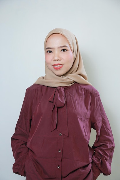 Glimlachende jonge Aziatische moslimvrouw voelt zich zelfverzekerd en vrolijk geïsoleerd op witte achtergrond