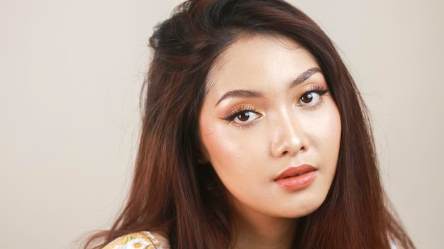 Glimlachende jonge Aziatische vrouw die make-up draagt die met witte achtergrond wordt geïsoleerd Schoonheidsconcept