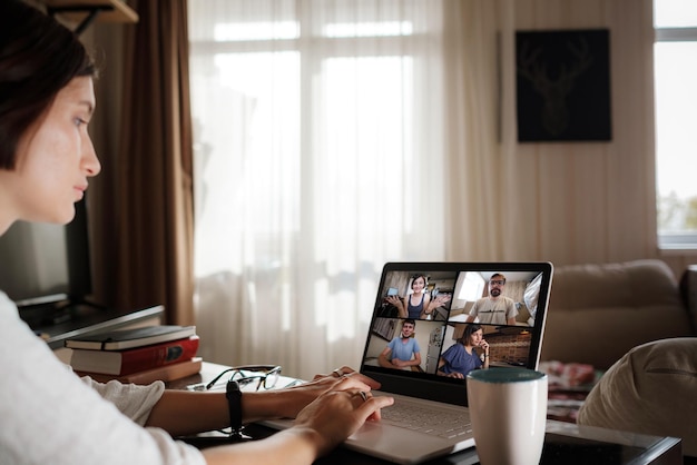 Glimlachende jonge aziatische vrouw die video belt op laptop