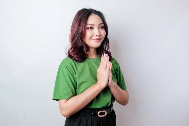 Glimlachende jonge Aziatische vrouw gebaren traditionele groet geïsoleerd op witte achtergrond