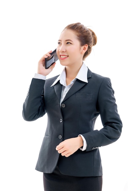 Glimlachende jonge Aziatische zakenvrouw in zwart pak en wit t-shirt praten op mobiele telefoon geïsoleerd op een witte achtergrond