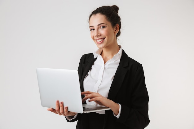 Glimlachende jonge bedrijfsvrouw die laptop met behulp van