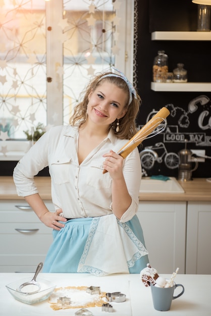 Glimlachende jonge chef-kok met toebehoren om te koken