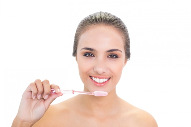 Glimlachende jonge donkerbruine vrouw die een tandenborstel houdt