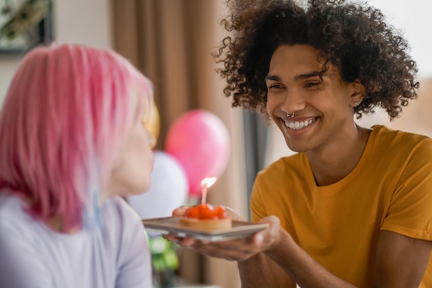 Glimlachende jonge man die een cadeau geeft aan zijn vriendin