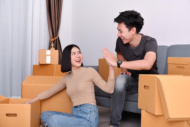 Glimlachende jonge man en vrouw geven high-five bij kartonnen dozen thuis