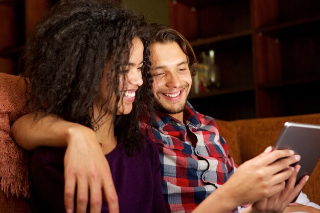 Glimlachende jonge man en vrouw thuis met digitale tablet