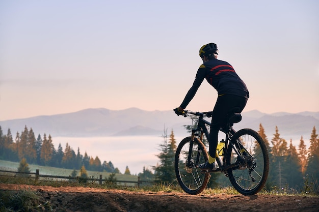 Glimlachende jonge man fietsten op bergweg