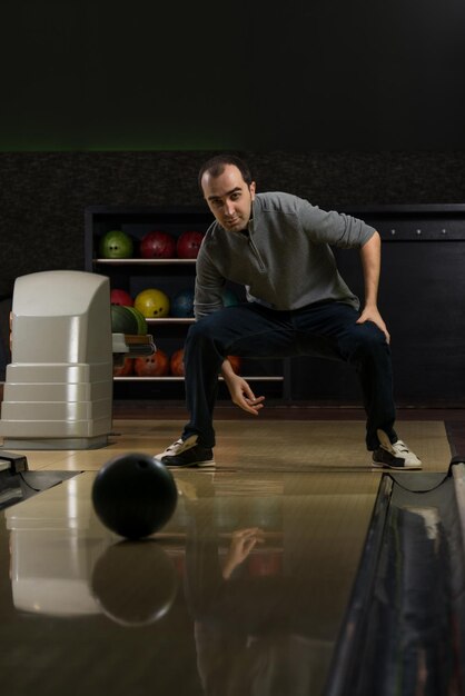 Glimlachende jonge man spelen met een bowlingbal