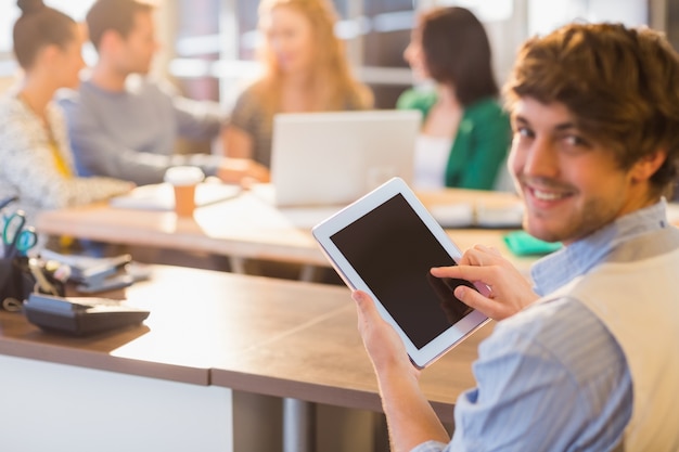 Glimlachende jonge mens die digitale tablet gebruikt