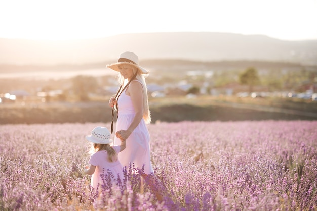 Glimlachende jonge moeder die met babydochter in lavendelgebied loopt