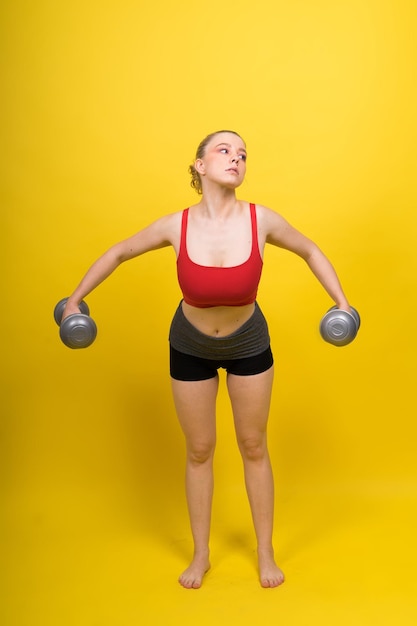 Glimlachende jonge mollige fitness sportieve verleidelijke vrouw die aan het trainen is met halters