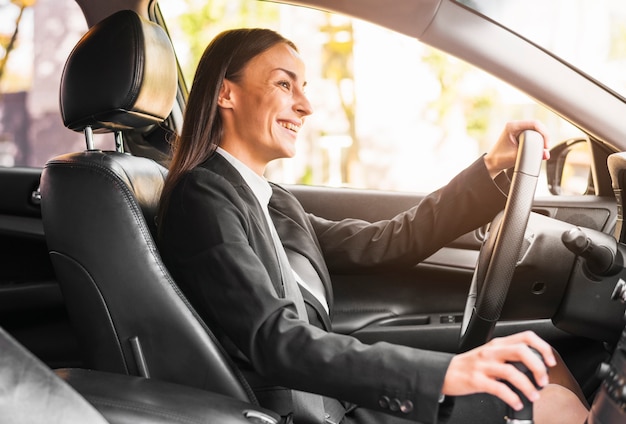 Glimlachende jonge onderneemster die een auto drijft