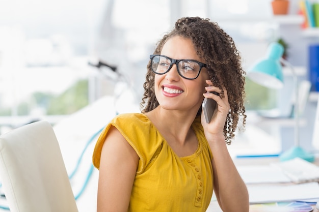 Glimlachende jonge onderneemster op de telefoon