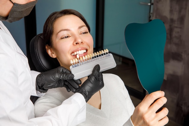 Glimlachende jonge vrouw cosmetische tanden bleken in een tandheelkundige kliniek selectie van de toon van de