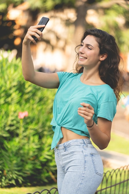 Glimlachende jonge vrouw die een selfie maakt in de stad.
