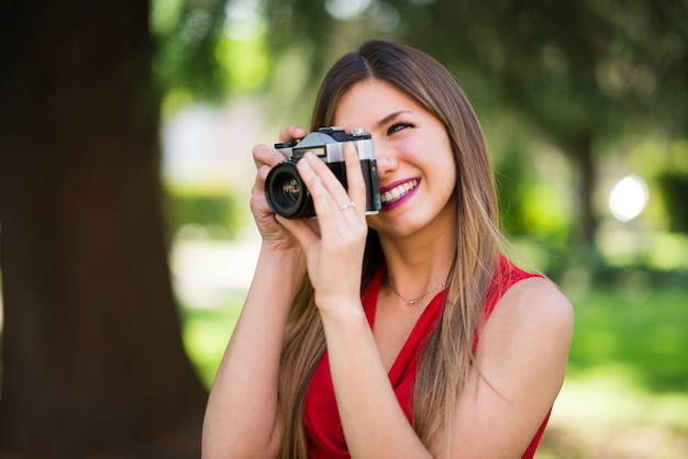 Glimlachende jonge vrouw die een uitstekende camera met behulp van