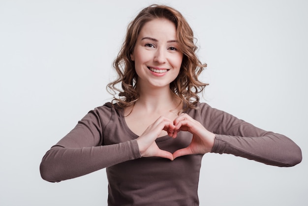 Glimlachende jonge vrouw die hart met vingers maken. .