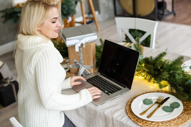 Glimlachende jonge vrouw die kerstinkopen doet op internet.