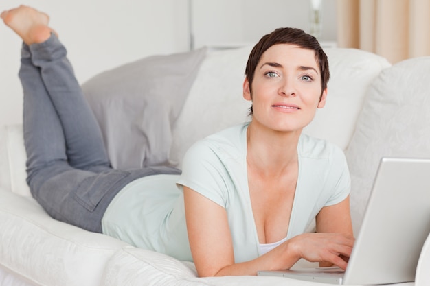 Glimlachende jonge vrouw die laptop met behulp van