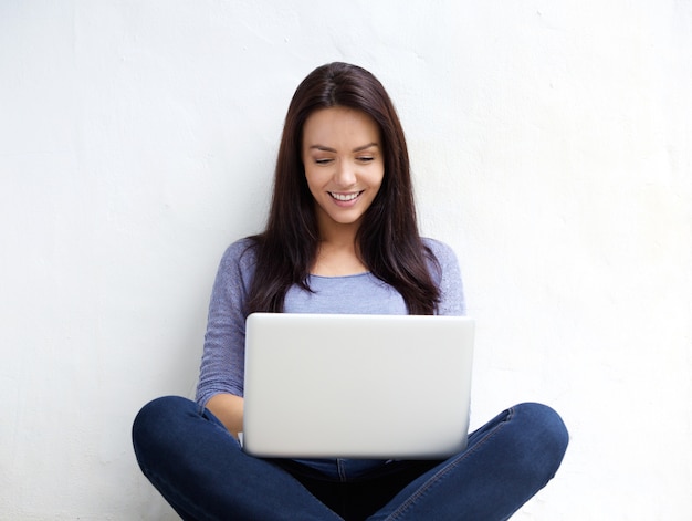 Glimlachende jonge vrouw die laptop met behulp van