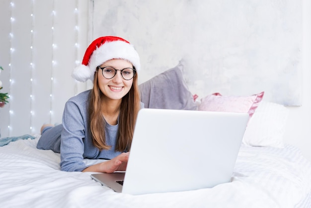 Glimlachende jonge vrouw die op haar laptop op internet surft voor kerstdeals terwijl ze