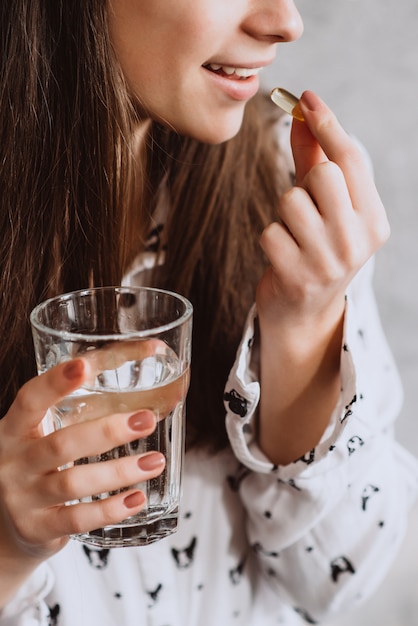 Glimlachende jonge vrouw die pillen met water neemt