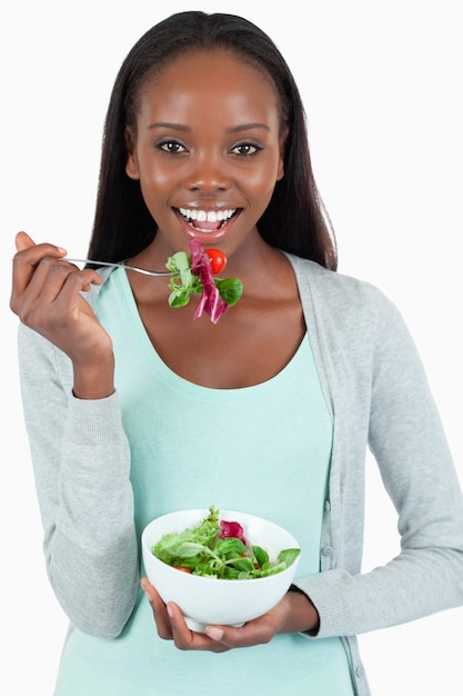 Glimlachende jonge vrouw die salade eet