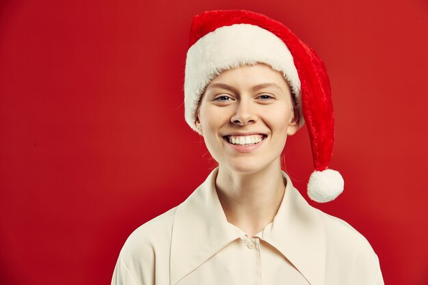 Glimlachende Jonge Vrouw die Santa Hat op Rood dragen