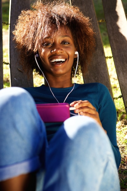 Glimlachende jonge vrouw die van muziek op slimme telefoon geniet