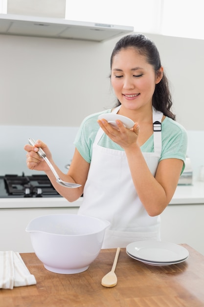 Glimlachende jonge vrouw die voedsel in keuken voorbereidt