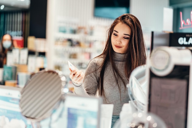 Glimlachende jonge vrouw die winkelt in een cosmetische winkel