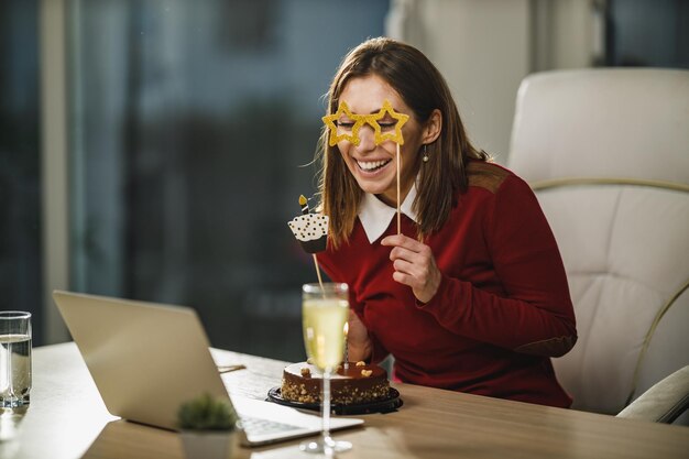 Glimlachende jonge vrouw heeft tijdens isolatie een online verjaardagsfeestje.