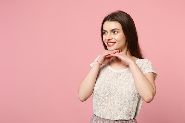 Glimlachende jonge vrouw in casual lichte kleding poseren geïsoleerd op roze achtergrond, studio portret. mensen oprechte emoties levensstijl concept. bespotten kopie ruimte. kijk opzij en leg de handsteun op de kin.