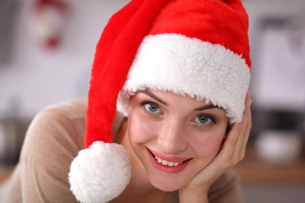 Glimlachende jonge vrouw in de keuken die op Kerstmisachtergrond wordt geïsoleerd