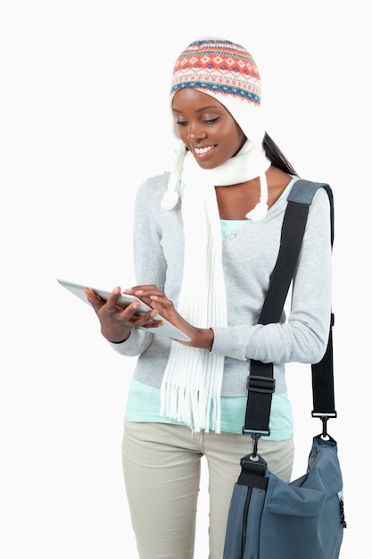 Glimlachende jonge vrouw in de winterkleren die haar tablet gebruiken